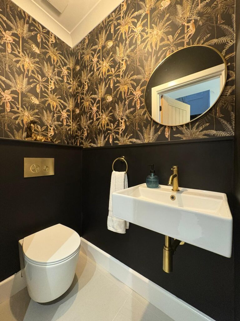 Low-down shot of a white sink, toilet floor and a circular mirror.