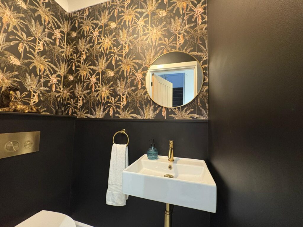 Close-up of a white sink with gold-toned plumbing and a ring towel holder.